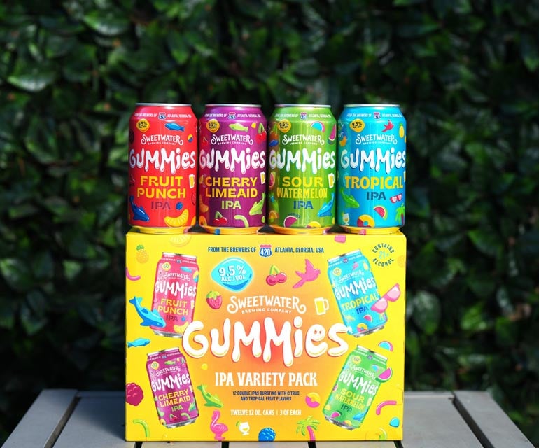 sweetwater gummies variety packs and cans in front of verdant hedgerow