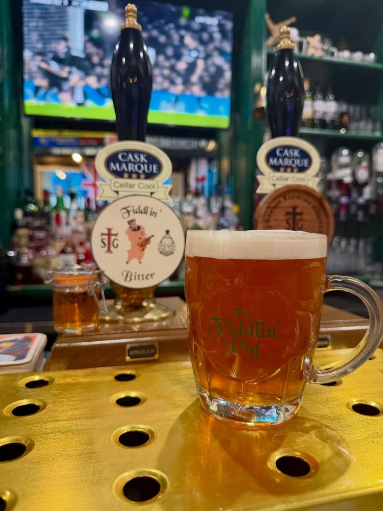 Mug of beer in front of two cask ale tap handles.