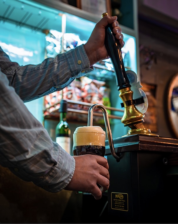 Dark beer being poured from cask beer pump