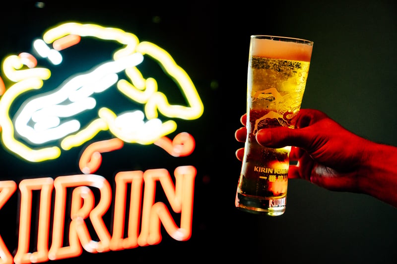 A beer glass held in front of a neon sign
