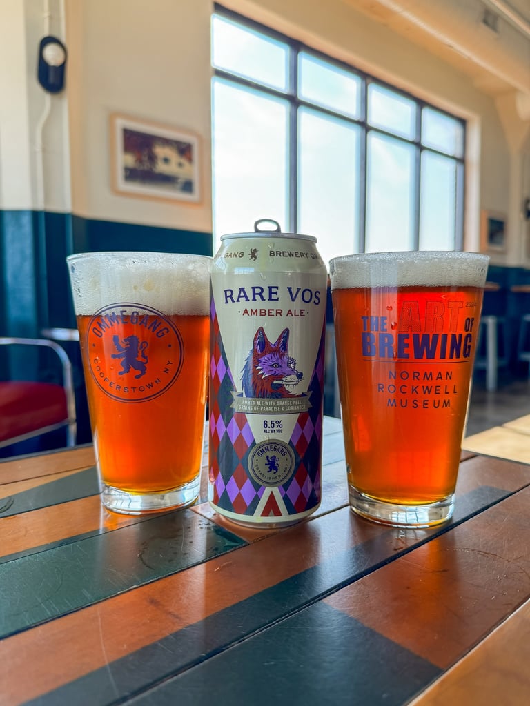 Two glasses of Ommegang Rare Vos next to a can on a table.