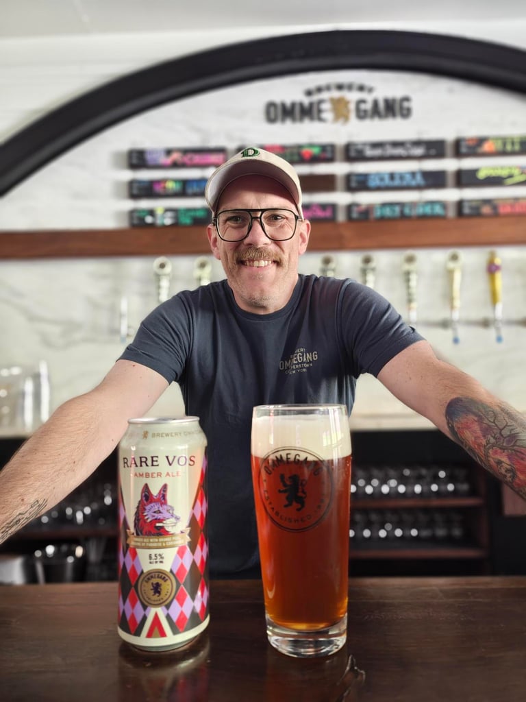 Man leaning over can and glass of Rare Vos